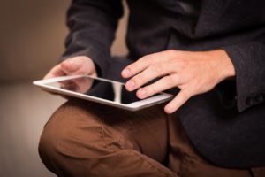 Hands hold and use a tablet. People who don't use email may appreciate having email set up for them.  